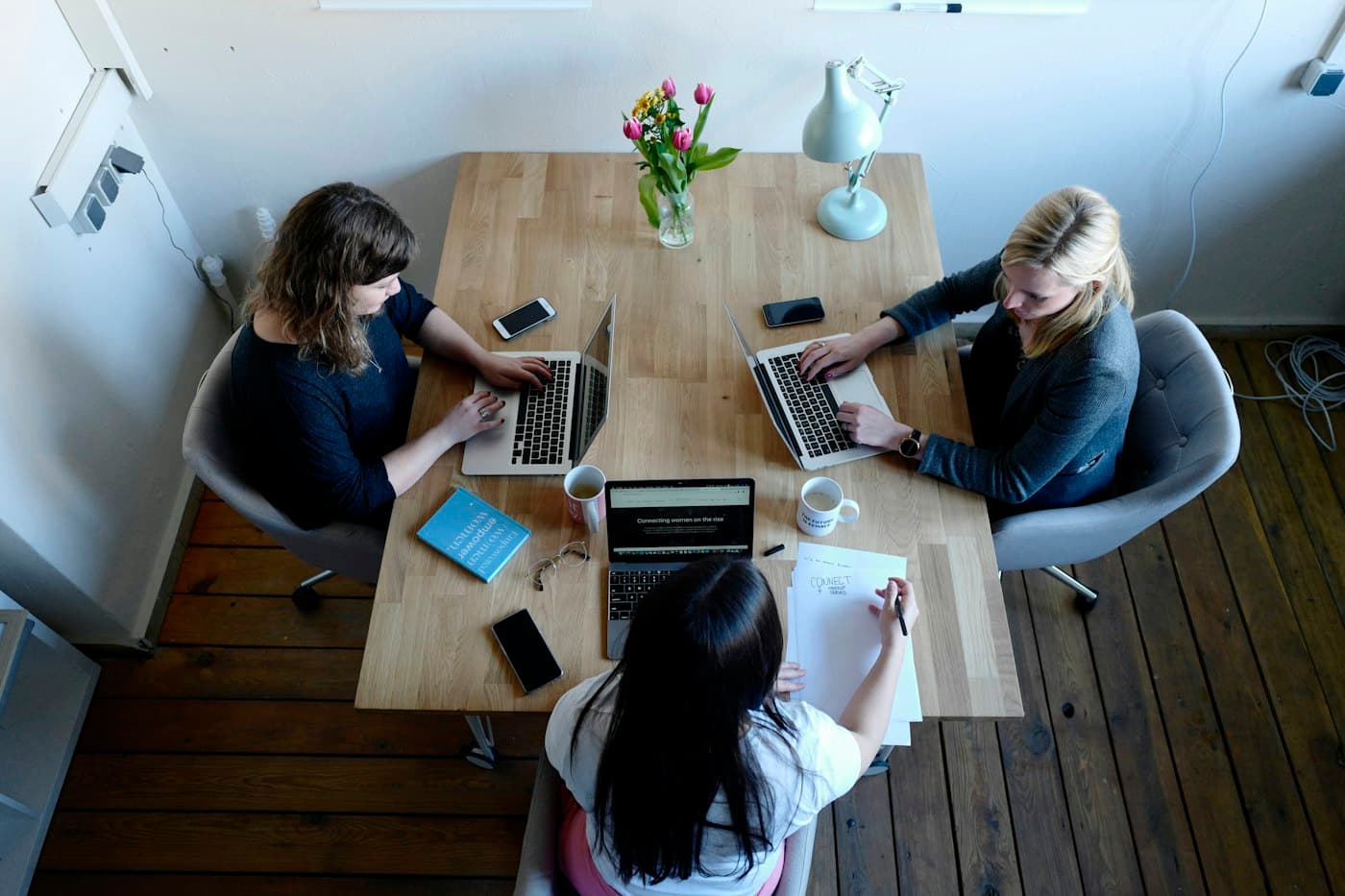 Tres personas trabajando juntas en una mesa con sus notebooks